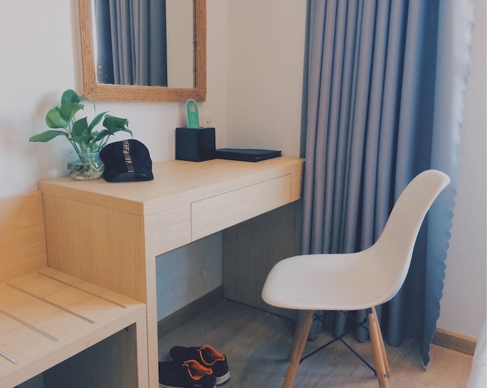 A study space consisting of a desk, chair, plant and mirror