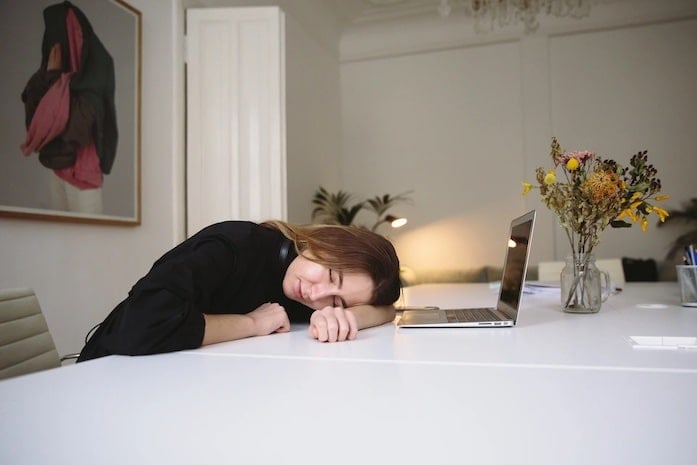A student with their head on their desk and eyes closed