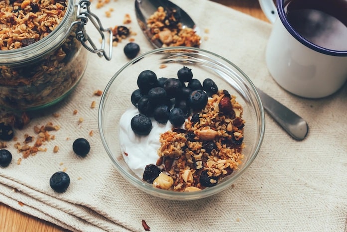 A bowl of yoghurt with granola and blueberries