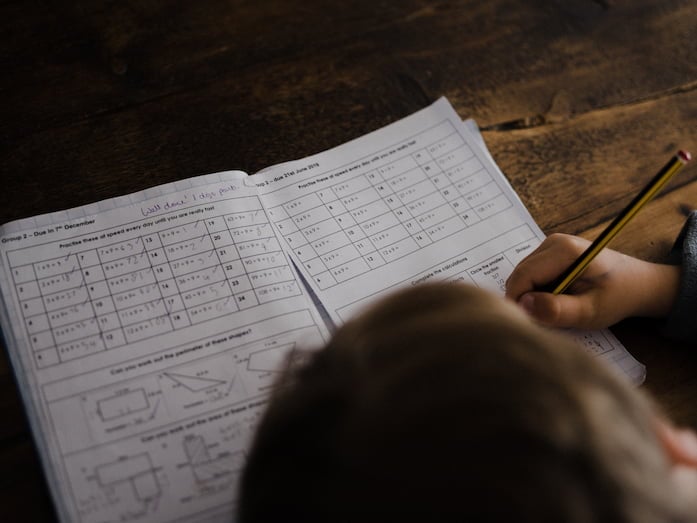 A child completing math answers in their notebook