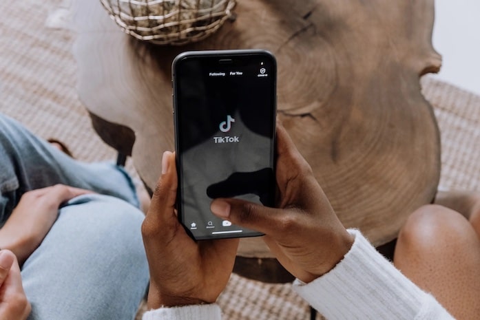 A pair of hands holding a phone displaying the TikTok app