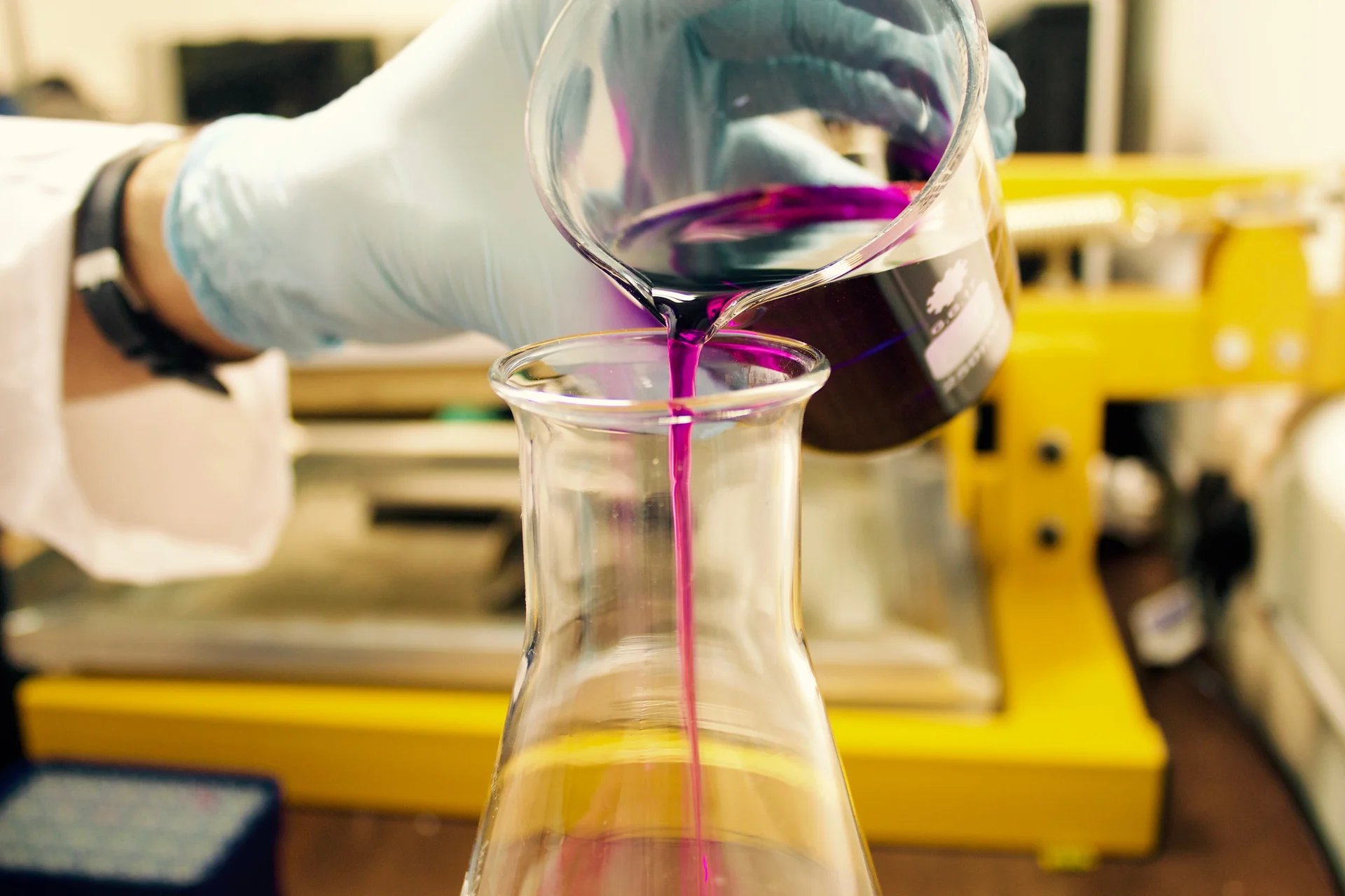 A student pours liquid into a beaker.