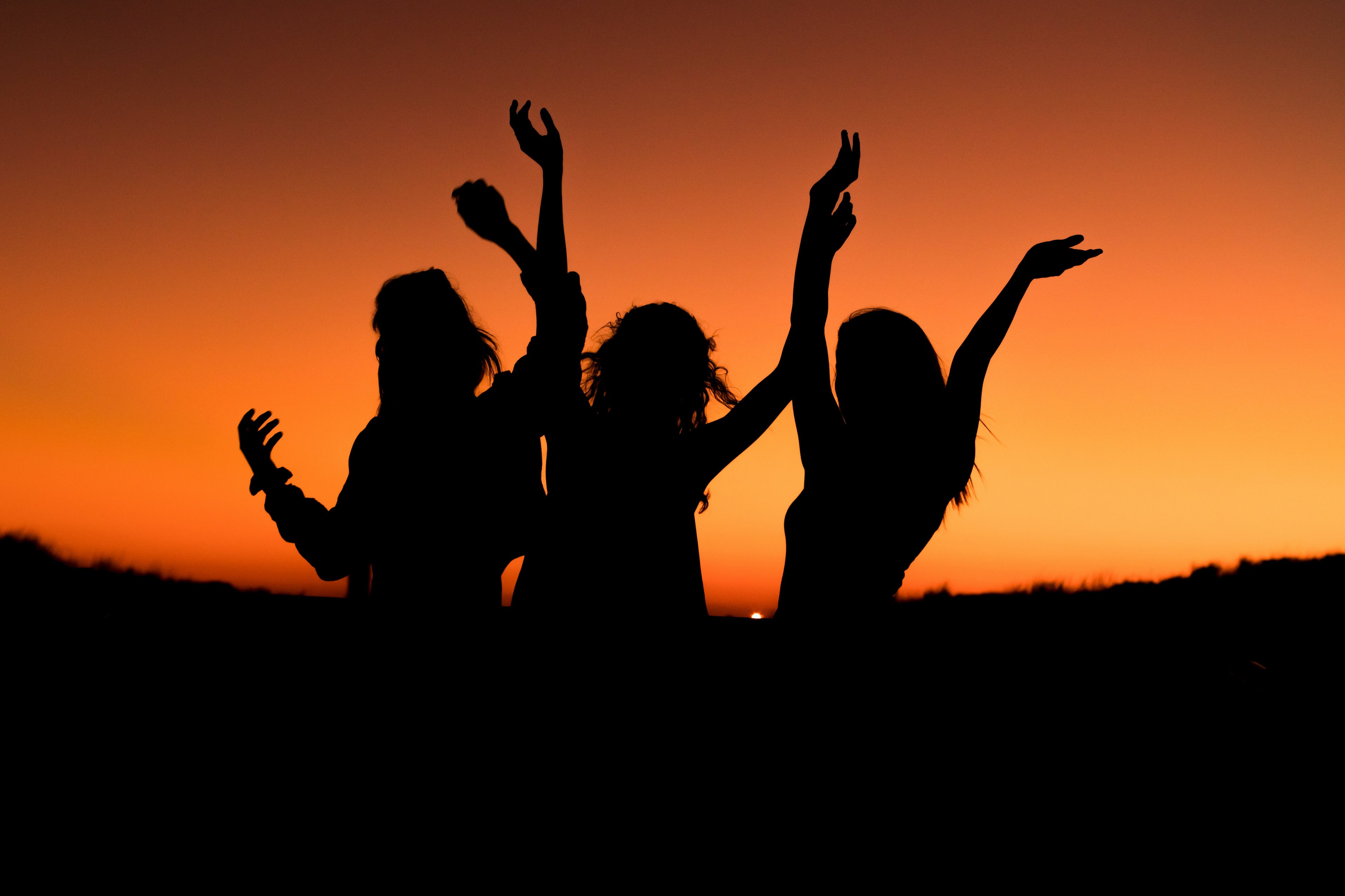 Students celebrate as the sun goes down behind them.