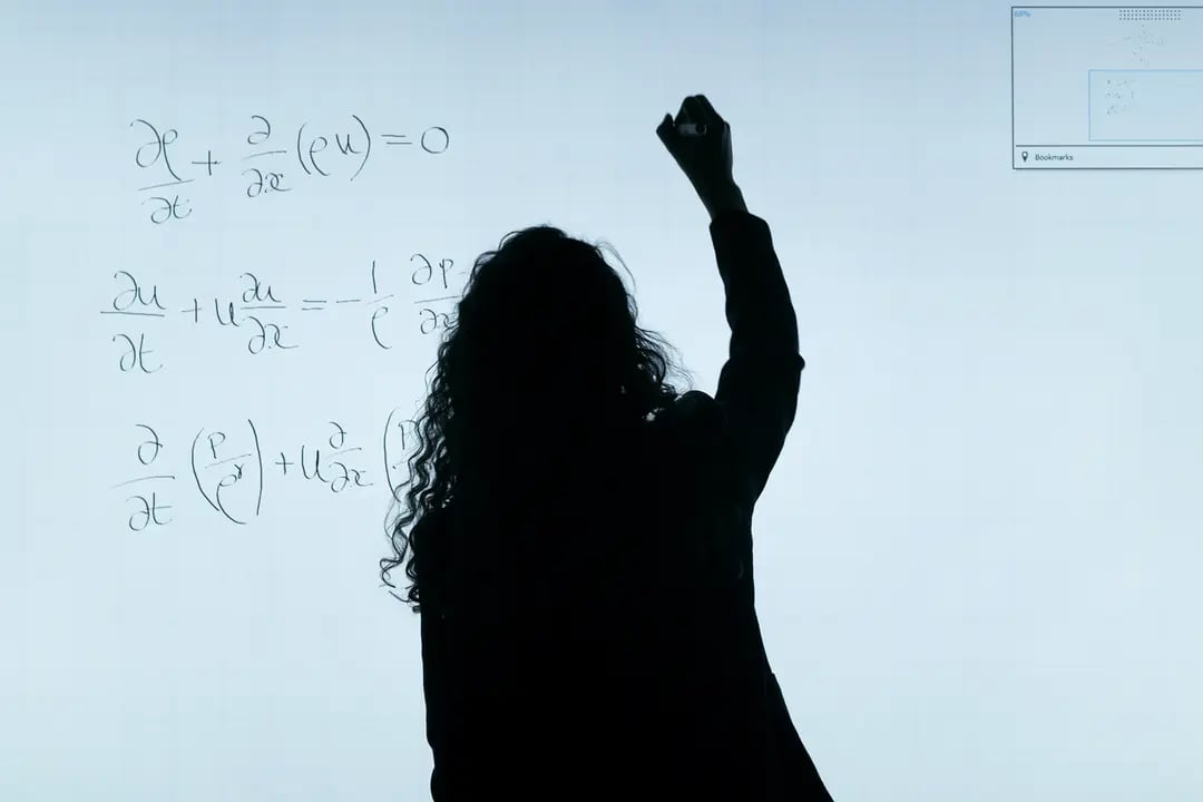 A student writes equations on a digital whiteboard.